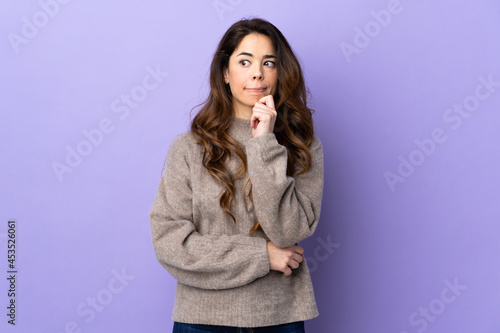 Woman over isolated purple background having doubts and thinking