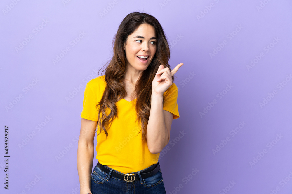Woman over isolated purple background intending to realizes the solution while lifting a finger up Woman over isolated purple background intending to realizes the solution while lifting a finger up