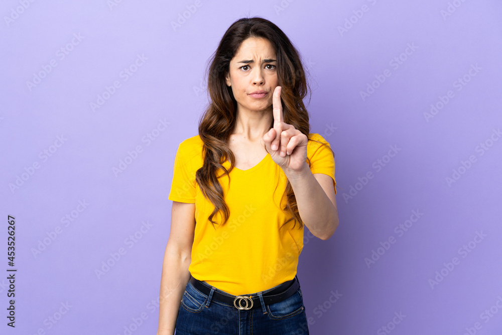 Woman over isolated purple background counting one with serious expression Woman over isolated purple background counting one with serious expression