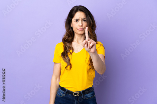 Woman over isolated purple background counting one with serious expression