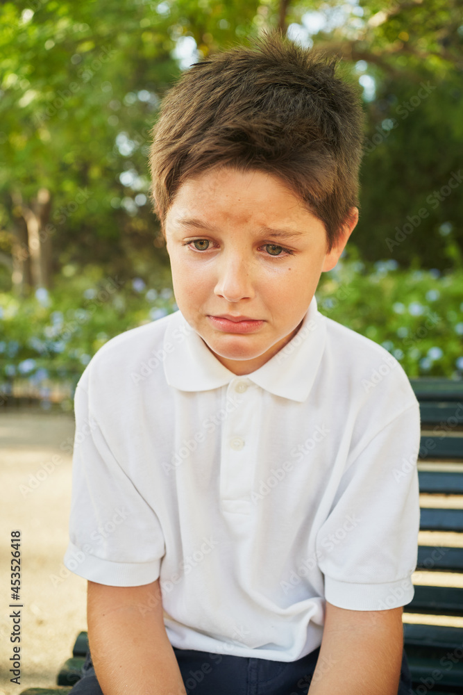 Lonely boy sitting and crying on bench