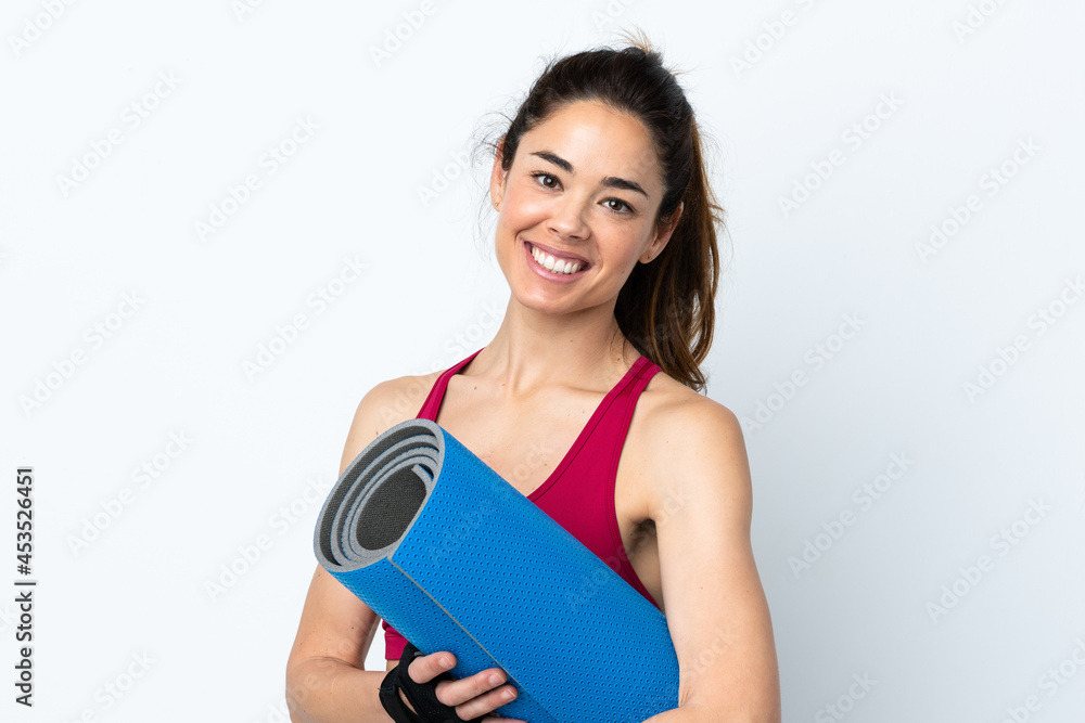 Sport woman over isolated white background with a mat and smiling Sport woman over isolated white background with a mat and smiling