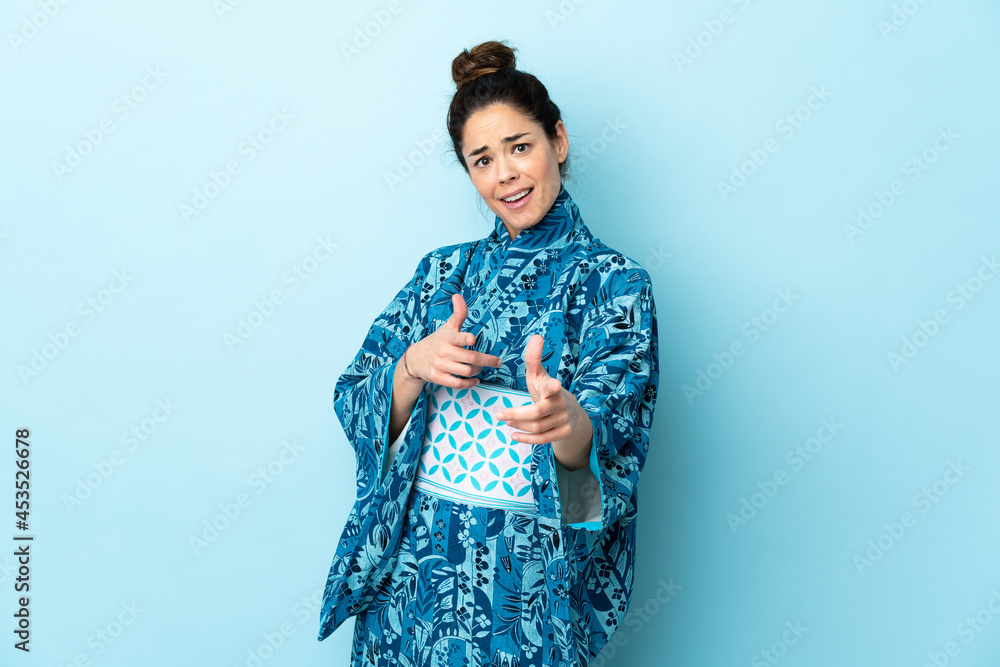 Woman wearing kimono over isolated background pointing to the front and smiling Woman wearing kimono over isolated background pointing to the front and smiling