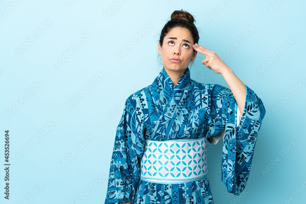 Woman wearing kimono over isolated background with problems making suicide gesture Woman wearing kimono over isolated background with problems making suicide gesture