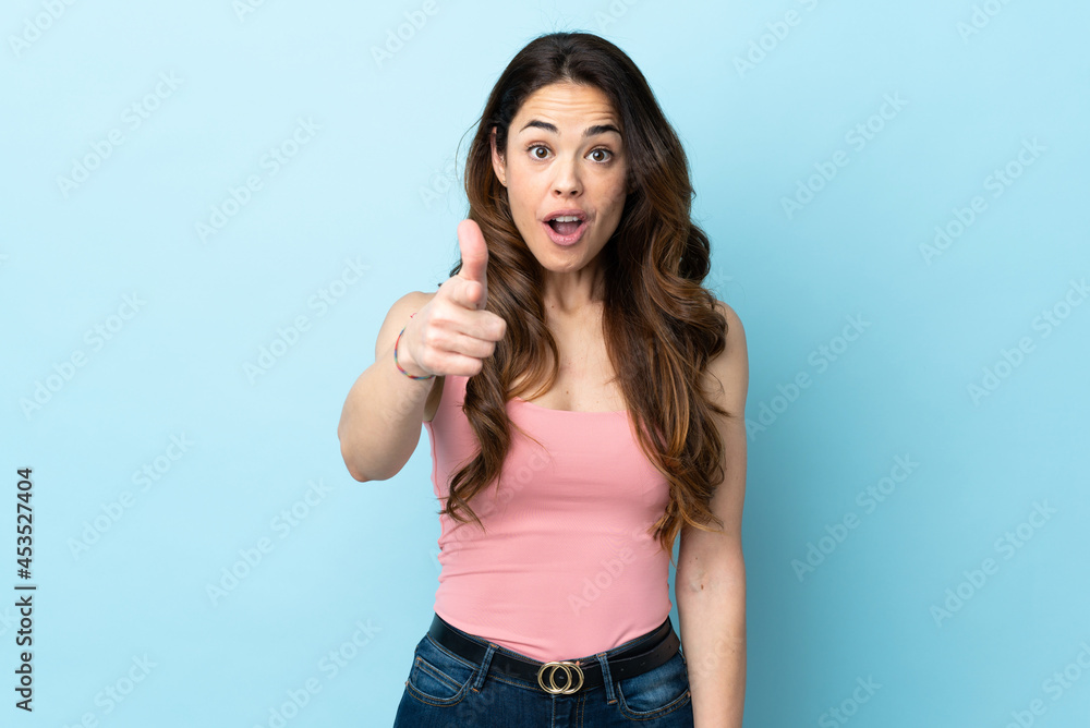 Fototapeta premium Woman over isolated blue background surprised and pointing front