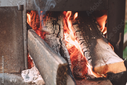 Open firebox of yard cauldron, with firewood burning in it photo