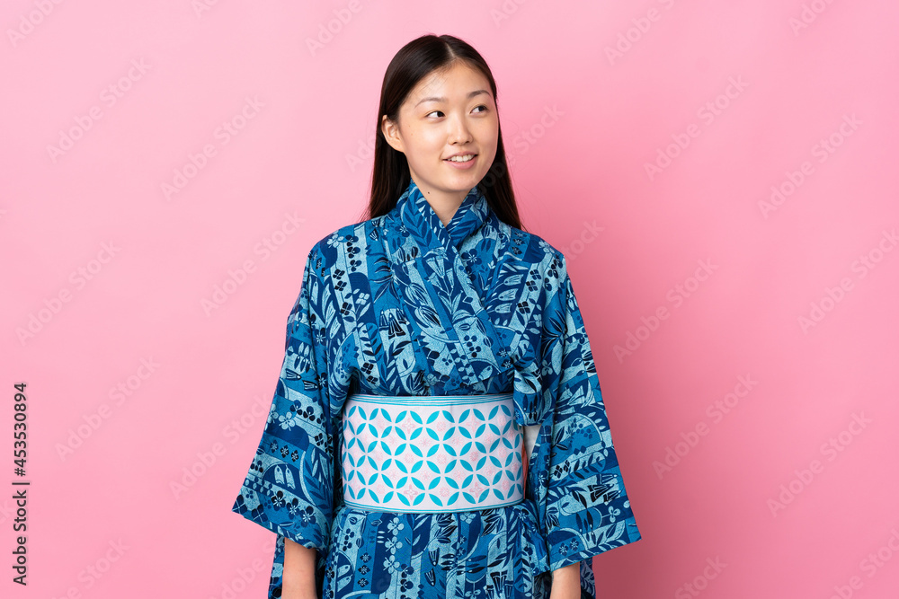 Young Chinese girl wearing kimono over isolated background thinking an idea while looking up Young Chinese girl wearing kimono over isolated background thinking an idea while looking up
