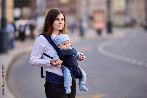 Sling helps woman to hold infant during walking. © grigvovan