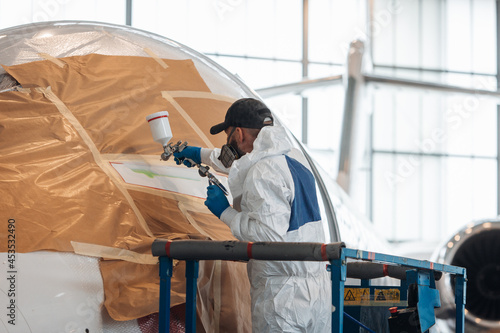 Valokuva Worker painting a plane inside big hangar