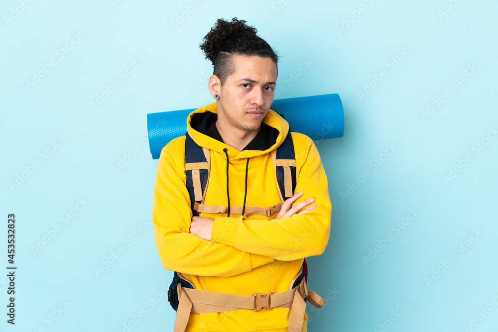 Young mountaineer man with a big backpack over isolated blue background thinking an idea Young mountaineer man with a big backpack over isolated blue background thinking an idea