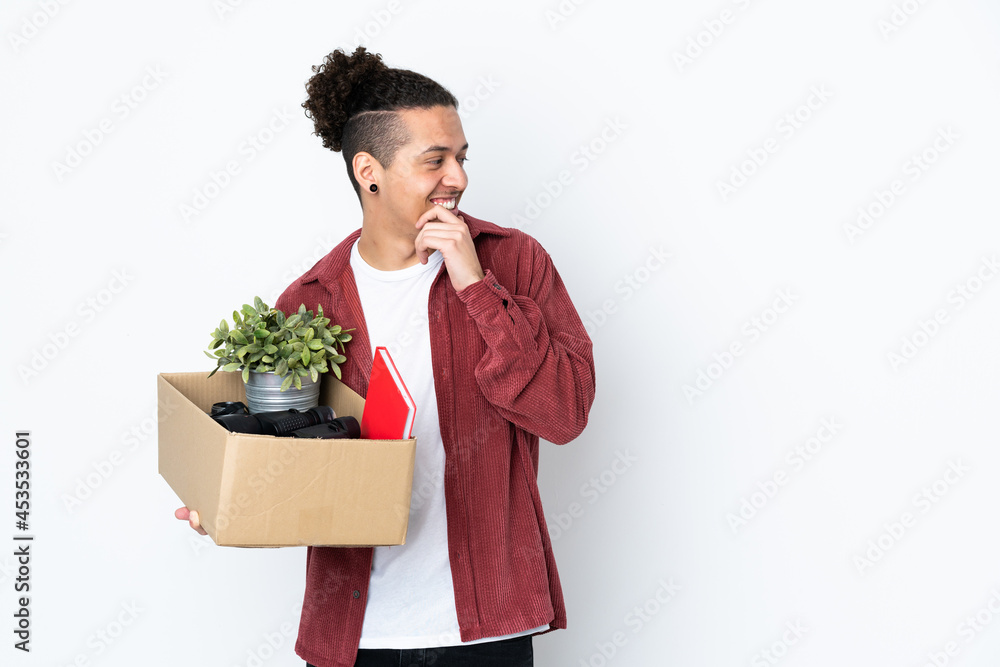 Caucasian man making a move while picking up a box full of things over isolated white background thinking an idea and looking side Caucasian man making a move while picking up a box full of things over isolated white background thinking an idea and looking side
