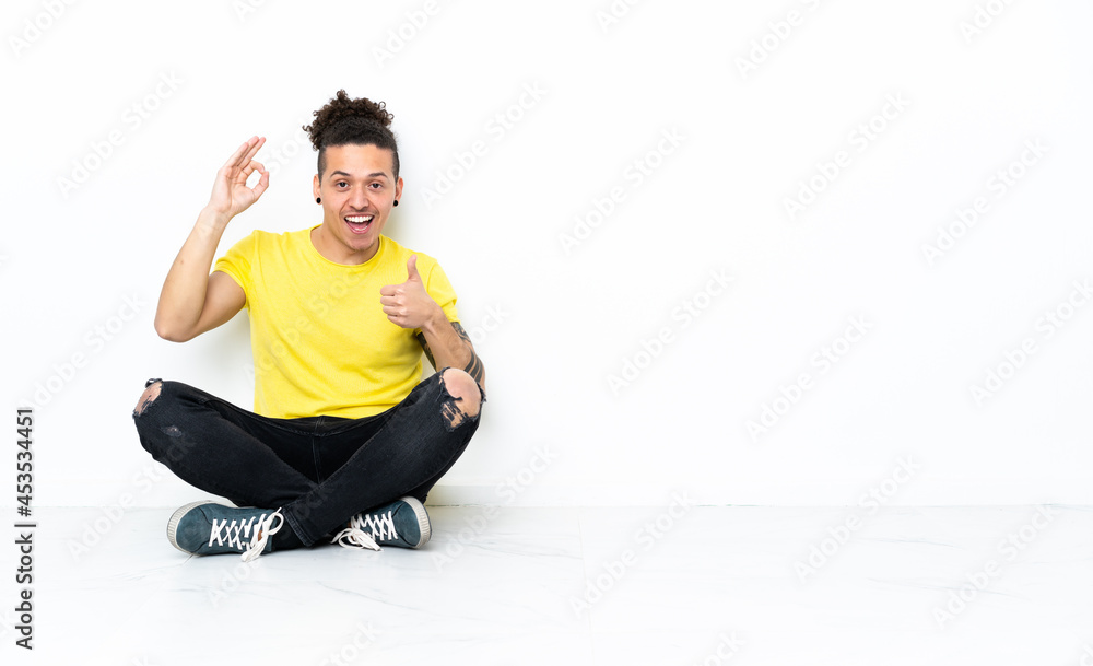 Caucasian man sitting on the floor showing ok sign and thumb up gesture Caucasian man sitting on the floor showing ok sign and thumb up gesture