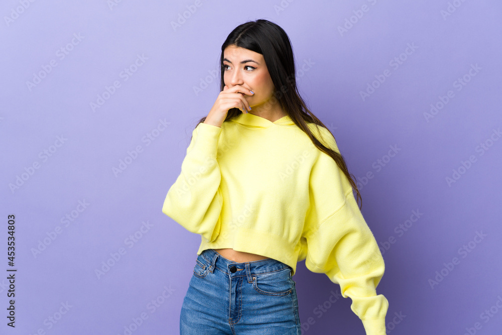 Young brunette woman over isolated purple background doing surprise gesture while looking to the side Young brunette woman over isolated purple background doing surprise gesture while looking to the side