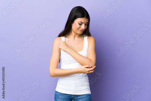 Young brunette woman over isolated purple background with pain in elbow