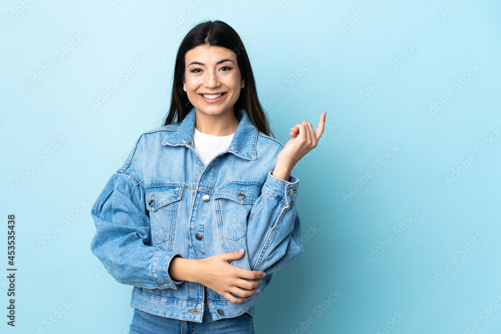 Young brunette girl over isolated blue background happy and pointing up Young brunette girl over isolated blue background happy and pointing up