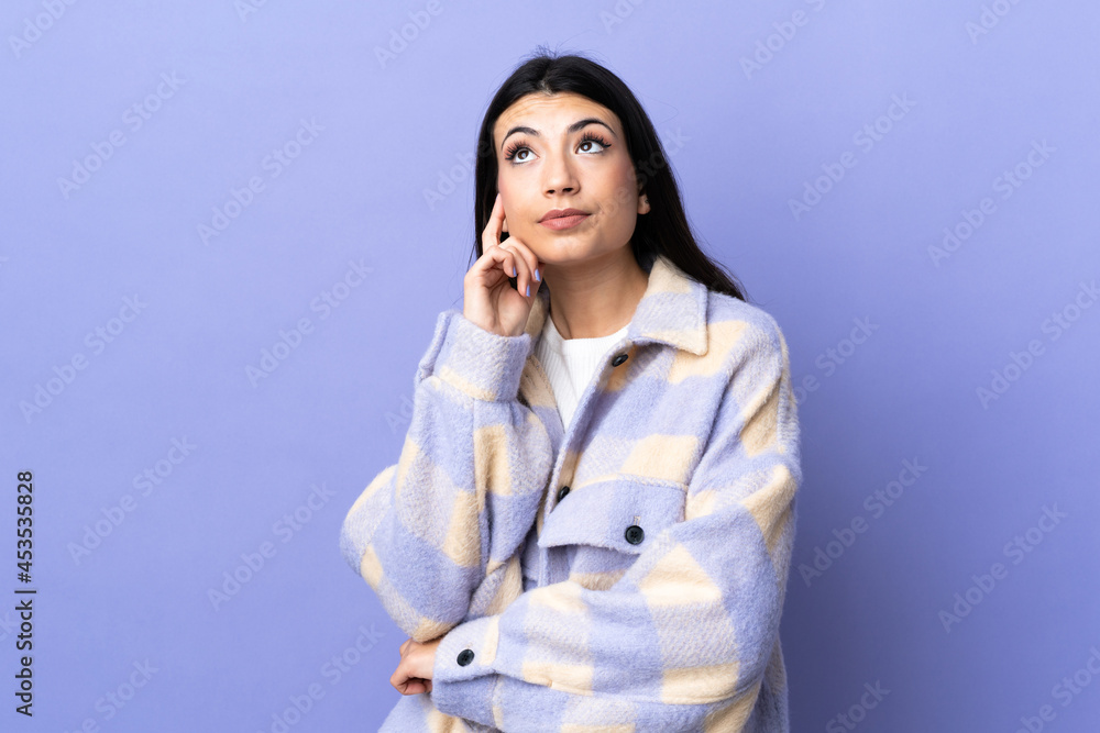 Young brunette woman over isolated purple background thinking an idea while looking up Young brunette woman over isolated purple background thinking an idea while looking up