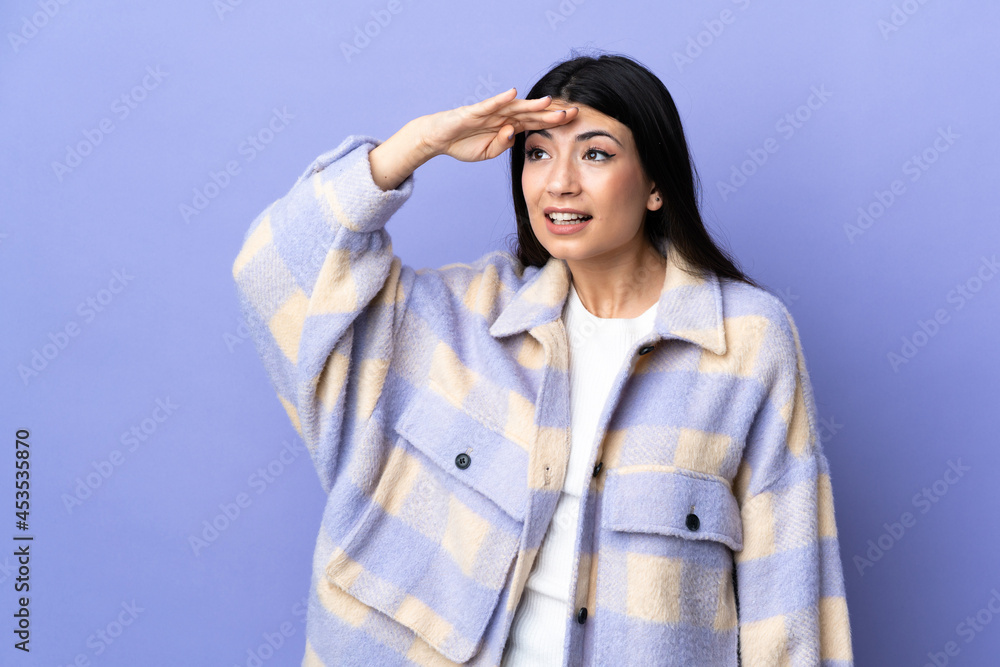 Young brunette woman over isolated purple background looking far away with hand to look something Young brunette woman over isolated purple background looking far away with hand to look something