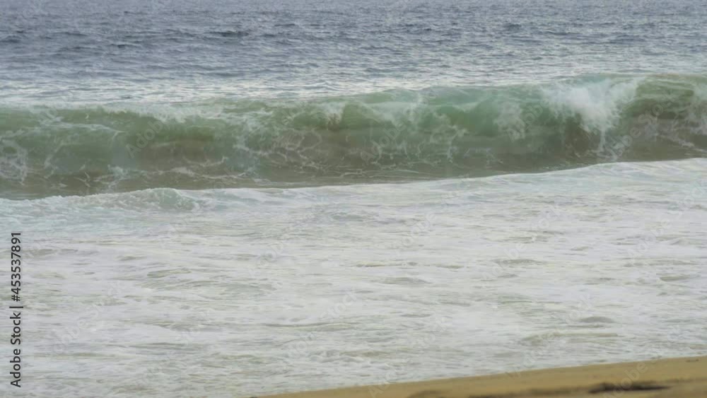 Pelícano pesca sobre el mar a la orilla de la playa, mientras vuela una fuerte ola impacta la playa. Pelícano pesca sobre el mar a la orilla de la playa, mientras vuela una fuerte ola impacta la playa.