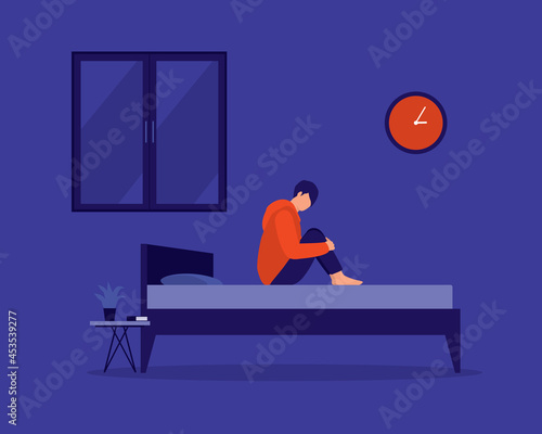 Young Depressed Man Hugging His Knees And Sitting On His Bed, Staying Awake And Having Trouble Sleeping At Night. Insomnia.