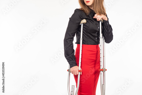 Woman with crutches. Person with limited mobility. Girl with metal crutches. Disabled woman on white background. Space for text on topic of disability. Sale of crutches for movement.