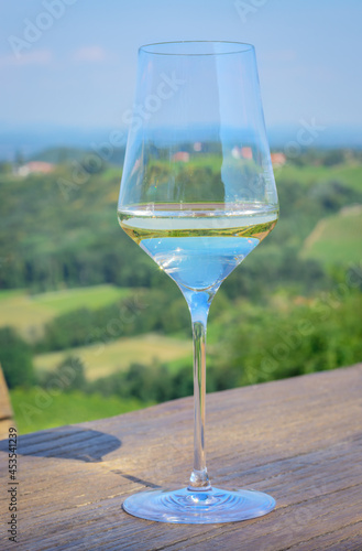 Glass with white wine on an outdoor table on a blurred background of hills