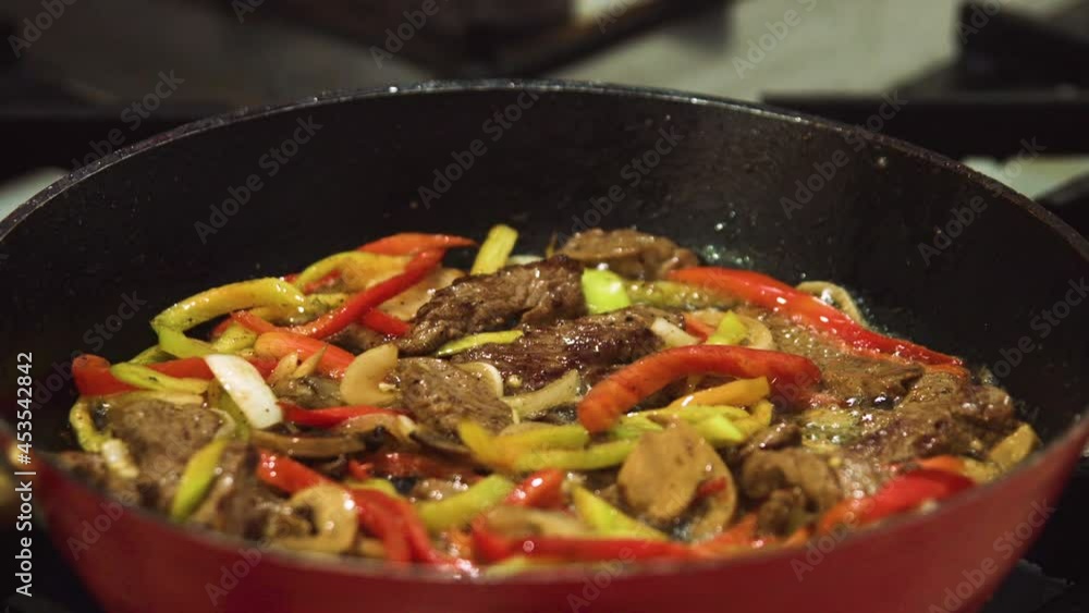 Meat cooked in a hot fire. Meat with vegetables cooked in a pan. Flames coming out of the pan. Cooking. Beef cooked in flames. Onion, green pepper, red pepper. Meat cooked in a hot fire. Meat with vegetables cooked in a pan. Flames coming out of the pan. Cooking. Beef cooked in flames. Onion, green pepper, red pepper.