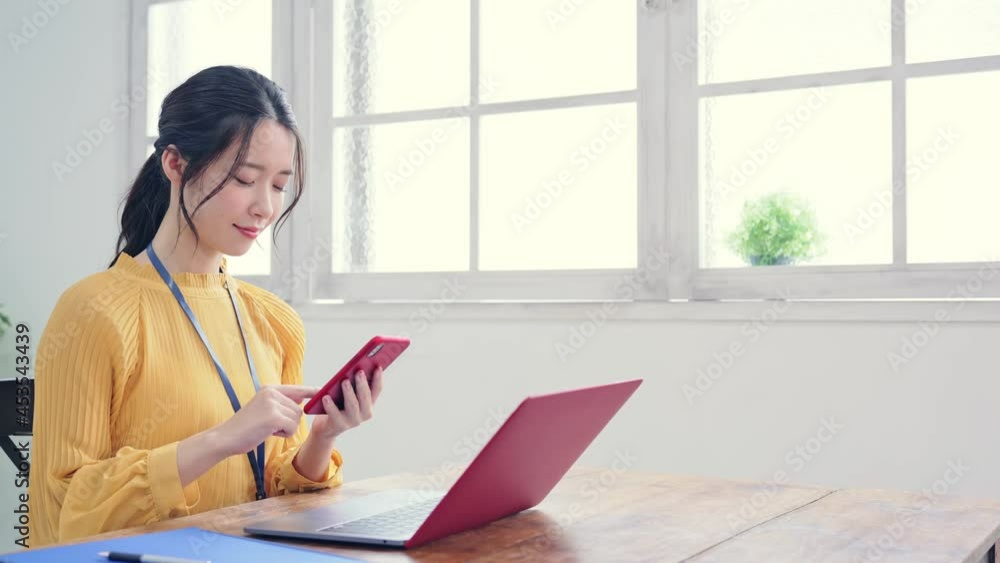 部屋でスマホを使う女性