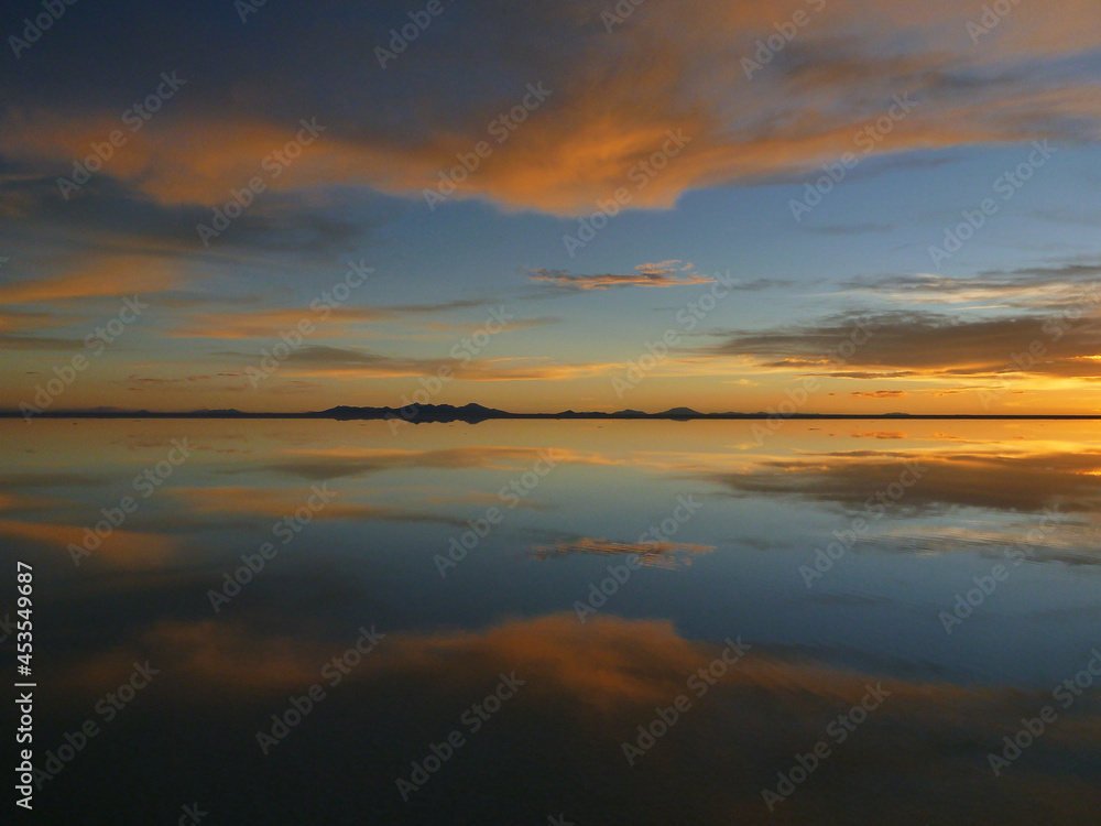 ボリビアのウユニ塩湖にて水面に鏡のように反射する夕日
