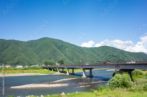 summer scenery of blue sky with clouds, mountain range, and brige over the chikuma river in nagano prefecture, japan