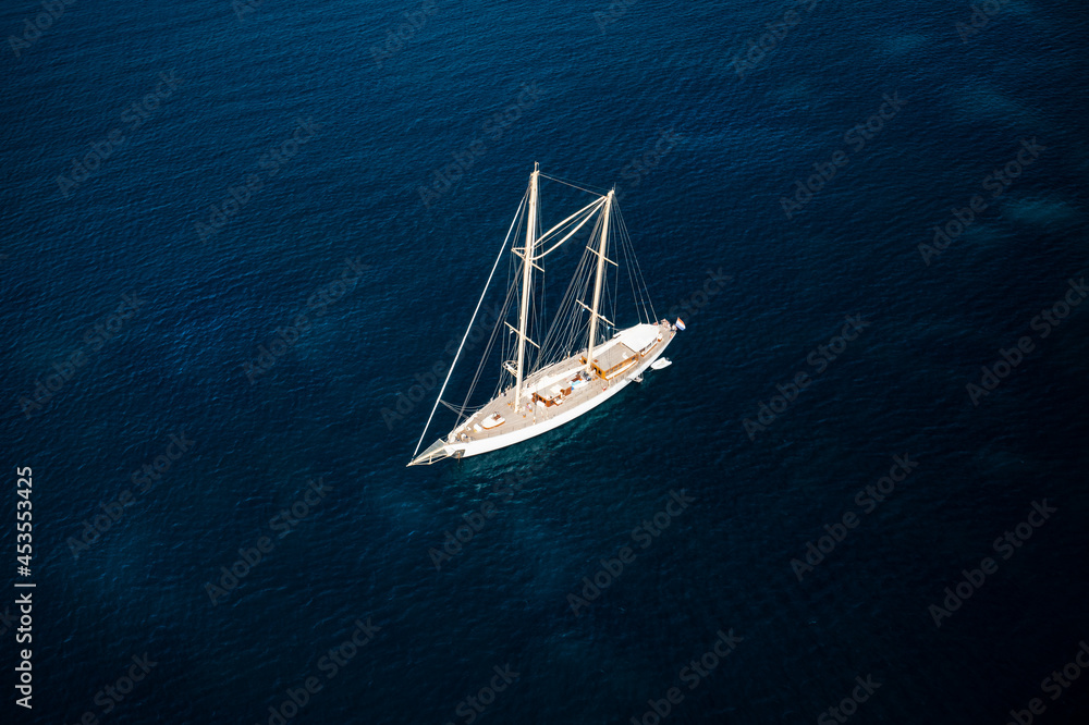 View from above, stunning aerial view of a luxury sailboat sailing on a blue water during a sunny day.Sardinia, Italy