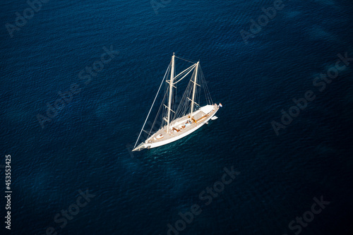 View from above, stunning aerial view of a luxury sailboat sailing on a blue water during a sunny day. Costa Smeralda, Sardinia, Italy © Travel Wild