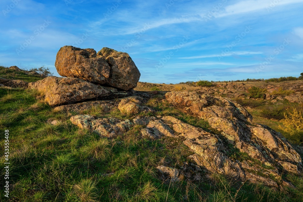 A small pile of stones in a green-yellow field against the background of a sky in Ukraine