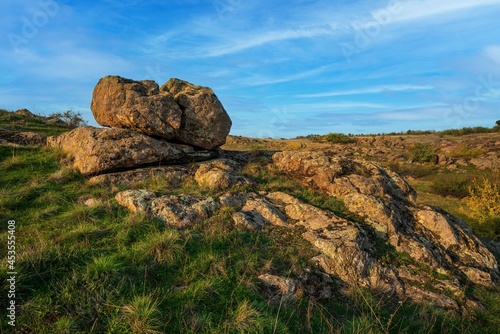 A small pile of stones in a green-yellow field against the background of a sky in Ukraine © YouraPechkin