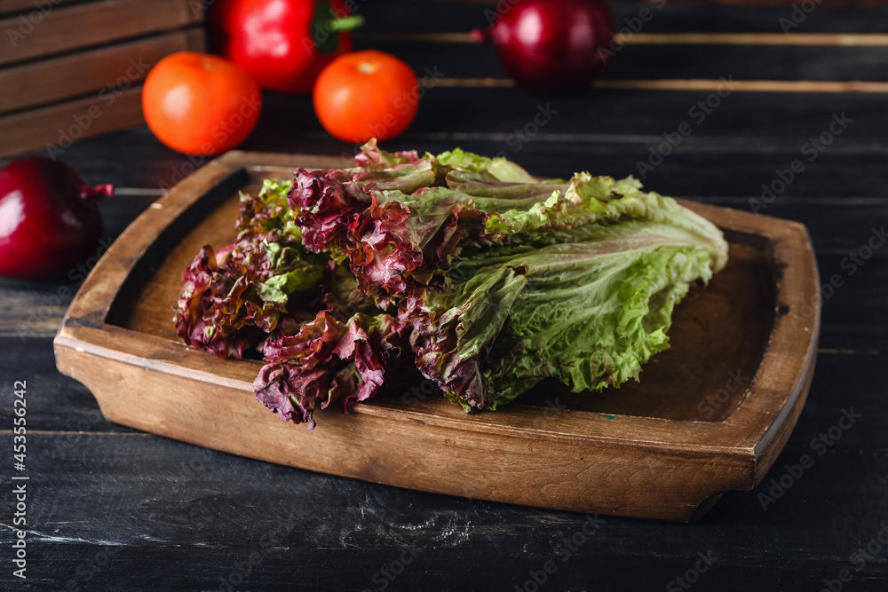 Board with fresh Lollo Rosso lettuce on wooden background