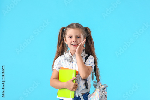 Cute little school girl on color background