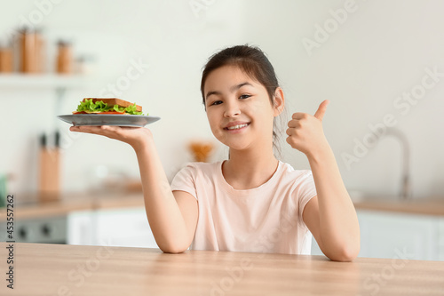 Happy little girl eating ta...