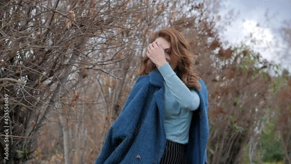 young red-haired woman in a blue coat and walks against the backdrop of the old city. portrait of a beautiful woman in the autumn city. young red-haired woman in a blue coat and walks against the backdrop of the old city. portrait of a beautiful woman in the autumn city.