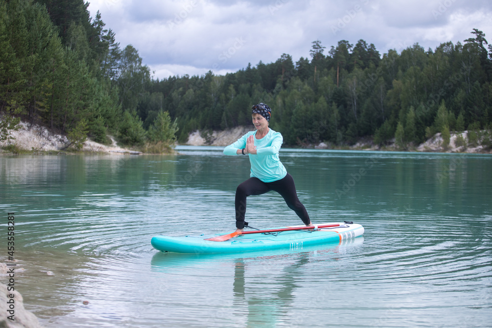 The girl does yoga on the glanders on the pond