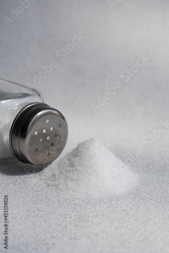 A pile of salt from salt shaker, concept excessive salt intake and white death