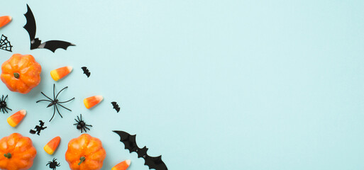 Top view photo of halloween decorations small pumpkins candy corn spiders web witch and bats silhouettes on isolated pastel blue background with copyspace