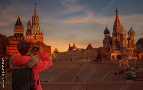 Back view of young man in red suit backpak photographer using a camera takeing a picture of view in Kremlin palace and St. Basil's Cathedral at Moscow,Russia photo