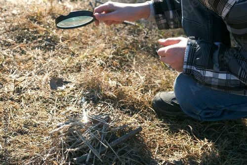 Wallpaper Mural Hand of a boy with a magnifying glass who is trying to set fire to the grass makes bonfire. Children's experiments in nature. The sun's rays pass through the magnifying glass and create a fire. Torontodigital.ca