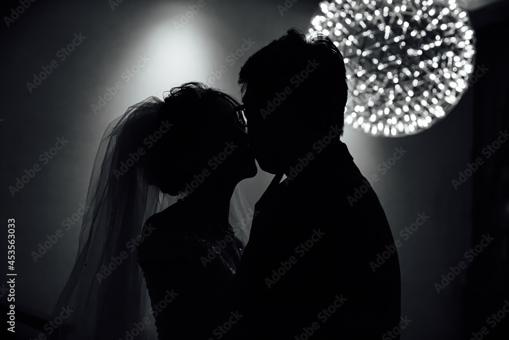 Silhouette of a couple kissing under dim light with modeling lighting
