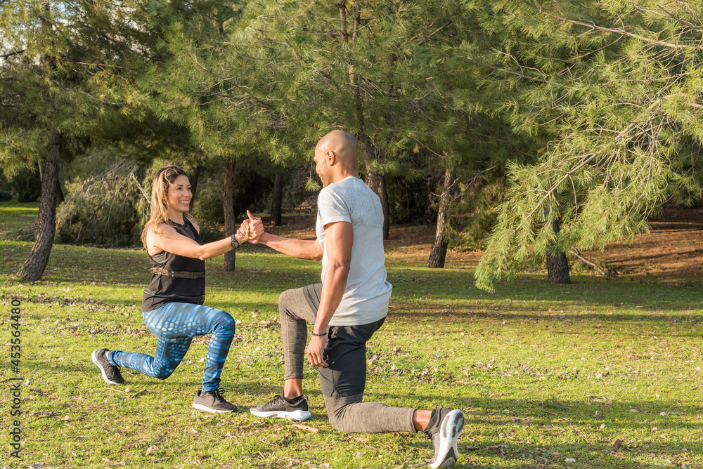 Obraz premium Fitness couple exercising by holding hands in the park