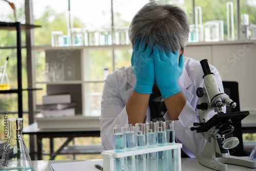 Senior scientist working in laboratory. Sad scientist despondent hands close face in workplace laboratory