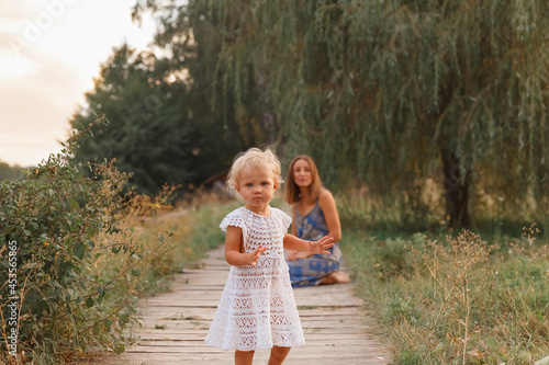 mother and daughter walk on the bridge by the water