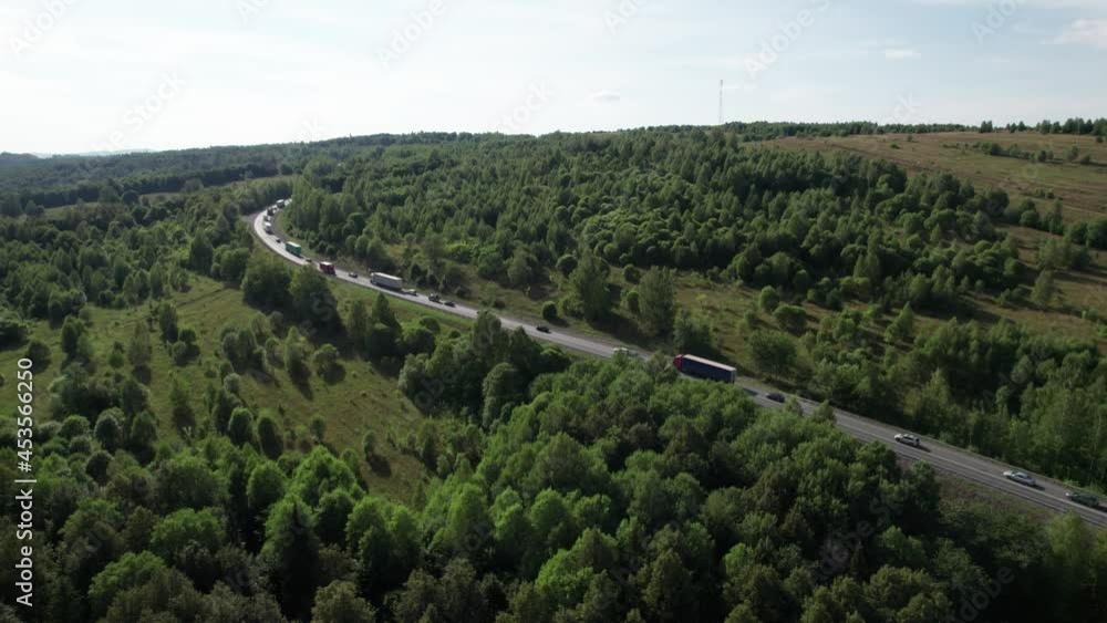 Aerial view of scenic road between green trees with pines on a sunny summer morning. Nature landscape in Siberia, Russia. A road passing through a coniferous forest, aerial shot from a drone. Aerial view of scenic road between green trees with pines on a sunny summer morning. Nature landscape in Siberia, Russia. A road passing through a coniferous forest, aerial shot from a drone.