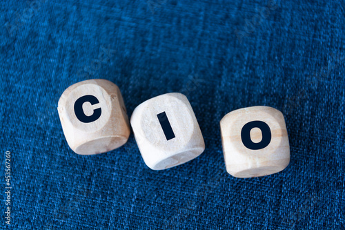 CIO written on wooden cubes - arranged in a vertical pyramid, grey and blue background, CIO - short for Chief Information Investment Officer, business concept photo