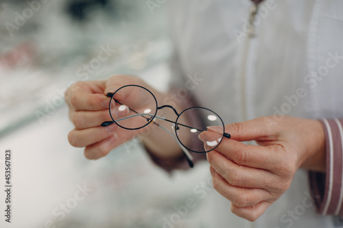 Women hand with trendy glasses lens. Eyeglasses transparent diopter.