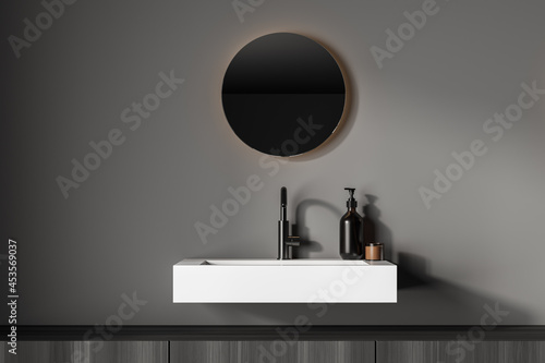 Dark bathroom interior with sink and round mirror